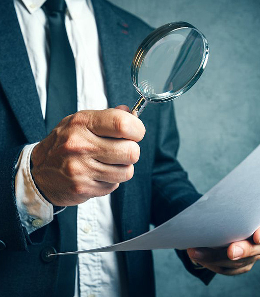 Private investigator in a suit holding a magnifying glass — Blue Falcons Investigation